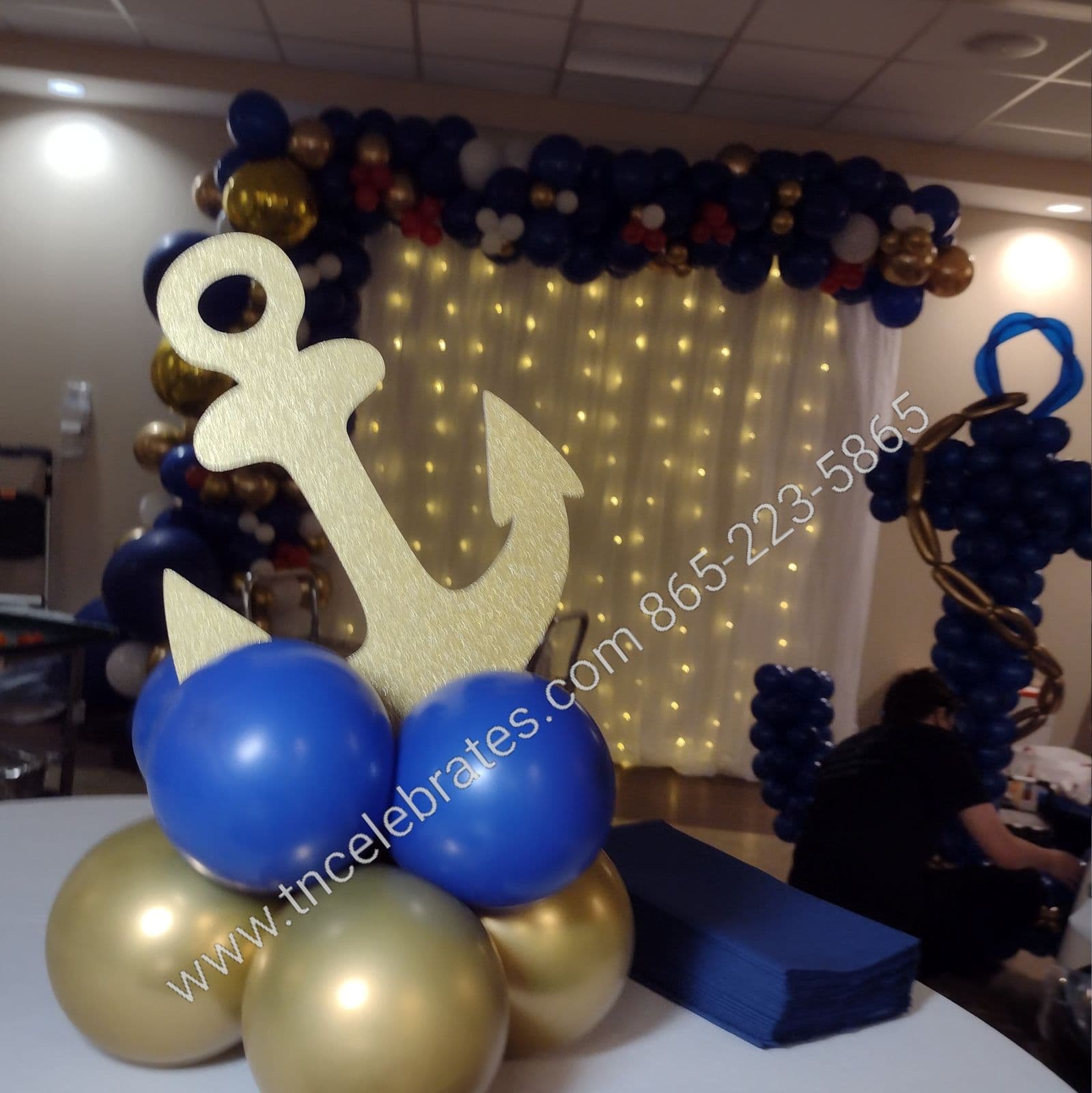balloon centerpiece with a golden anchor, balloon sculpture of an anchor in the background, with a balloon arch and backdrop
