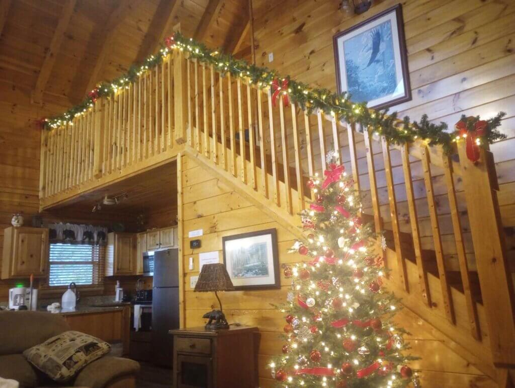 Pigeon Forge Christmas Cabin with lit up tree and lit up garland going up the stairs