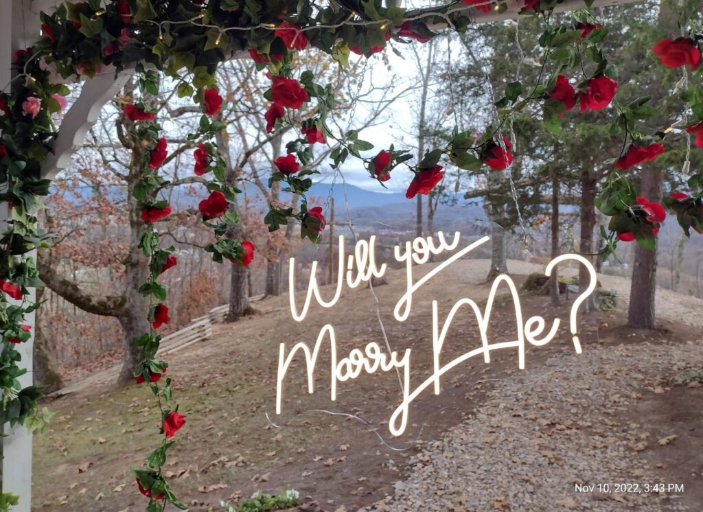 Marriage Proposal in Gatlinburg, with flower garlands and a lit sign "Will You Marry Me"